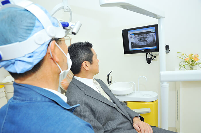 治療経過をモニターでみる歯科医師と患者